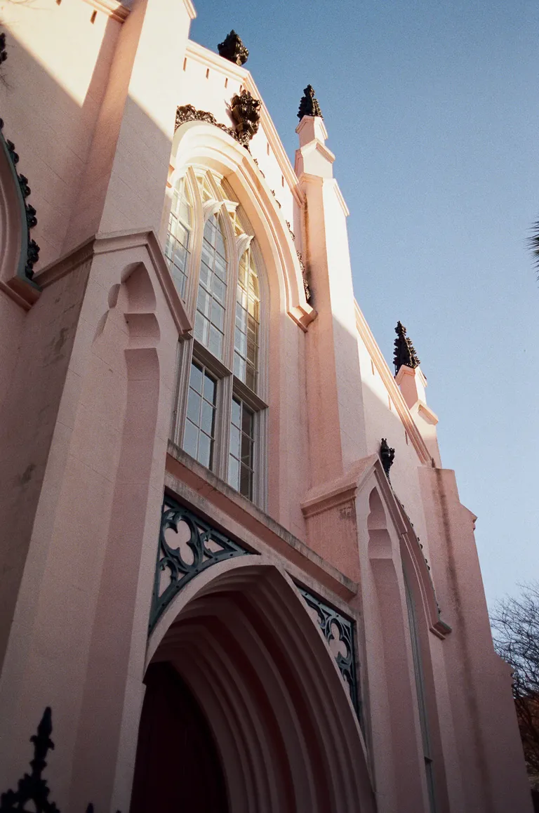 The pink facade of a Gothic church against a blue sky