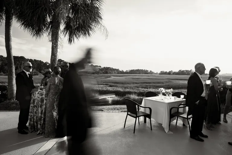 Guests mingling at an outdoor reception at sunset, black and white
