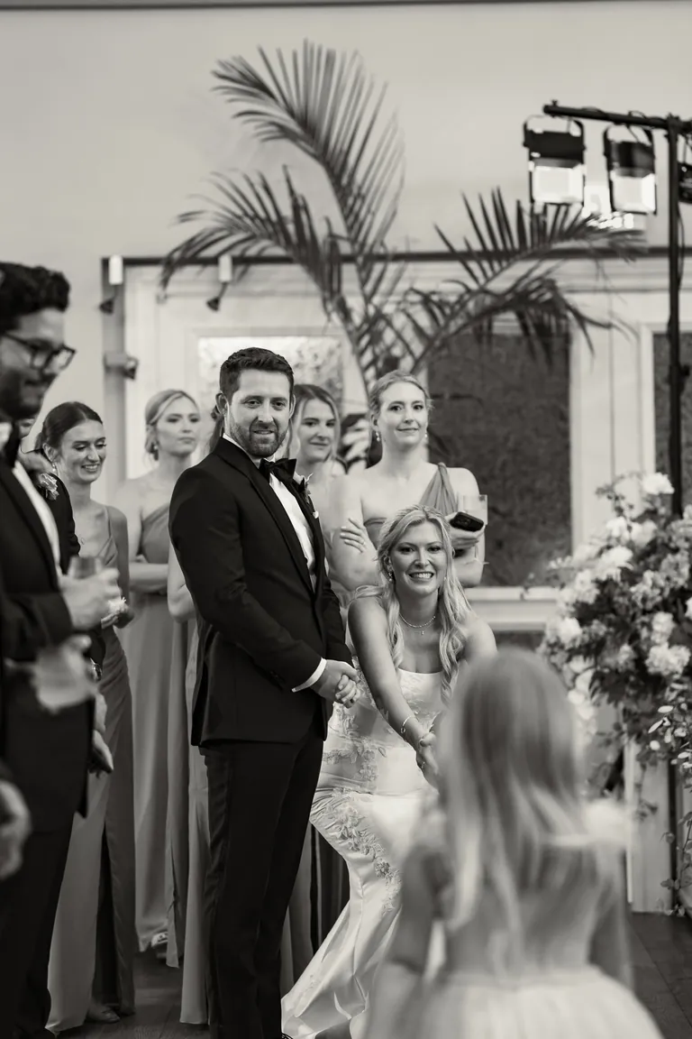 The groom glancing back at his bride during the ceremony, black and white